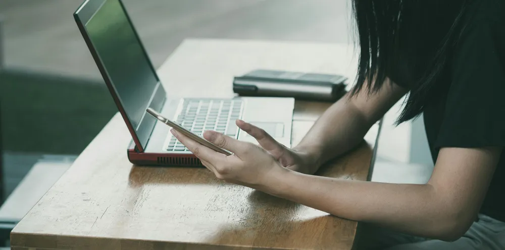 Eine Frau ist an Ihrem Laptop und Handy beschäftigt