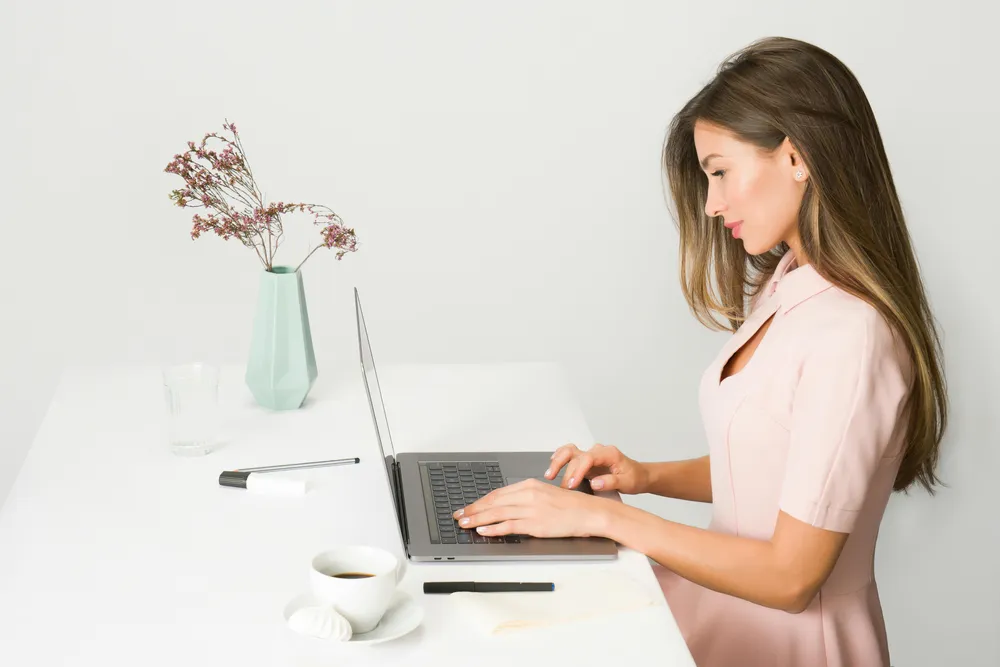 Eine Frau sitzt an einem Schreibtisch und arbeitet an einem Laptop.